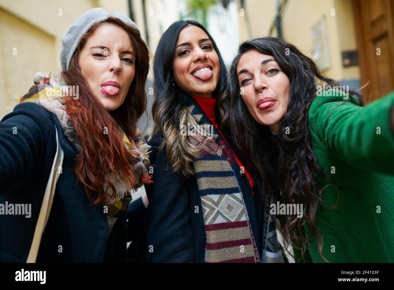 Multiethnische Gruppe von Frauen, die ein Selfie-Foto machen und ihre Zungen im Freien herausstechen. Eine Gruppe von Frauen, die ein Selfie-Foto machen, das aus ihren Zungen ragt Stockfoto
