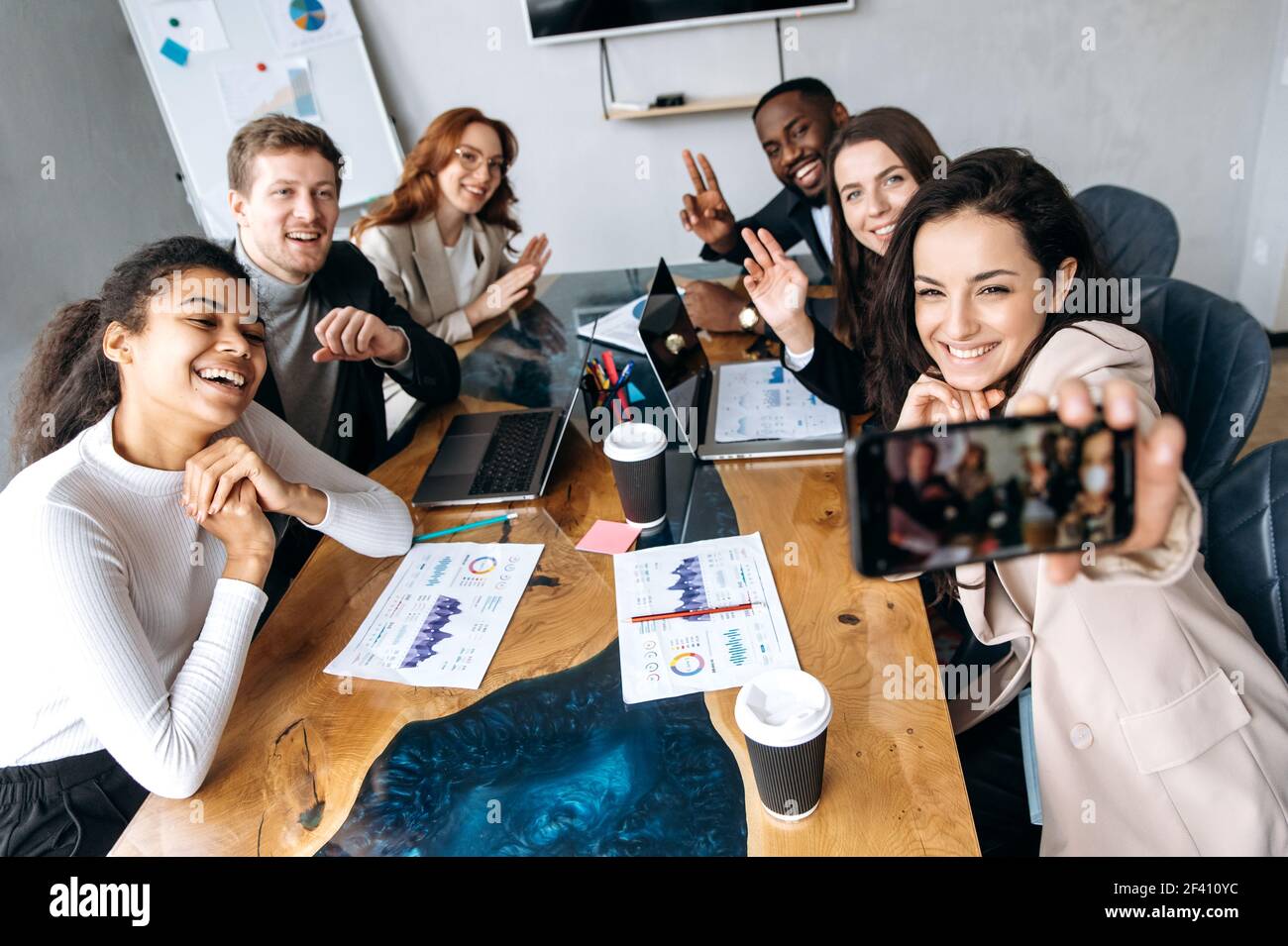 Glückliche Geschäftsleute, die ein GruppenSelfie beim Briefing-Meeting machen, lächeln. Selbstbewusste Kollegen haben erfolgreiche Verhandlungen abgeschlossen, Arbeitsergebnisse genossen, Partnerschaftskonzept Stockfoto