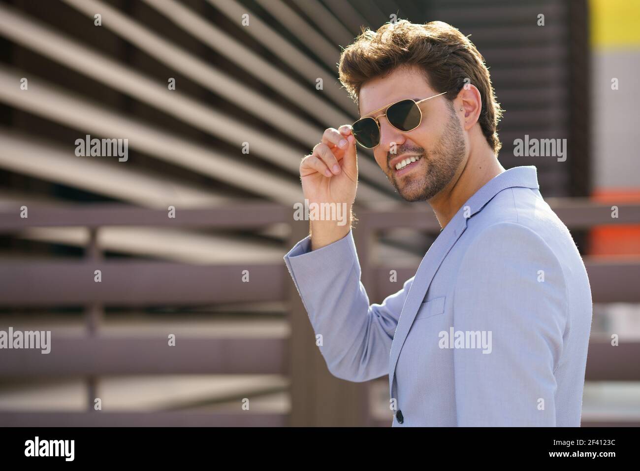 Junger Mann, Modelmodell, trägt Sonnenbrille im städtischen Hintergrund. Junger schöner Mann trägt Sonnenbrille im städtischen Hintergrund Stockfoto