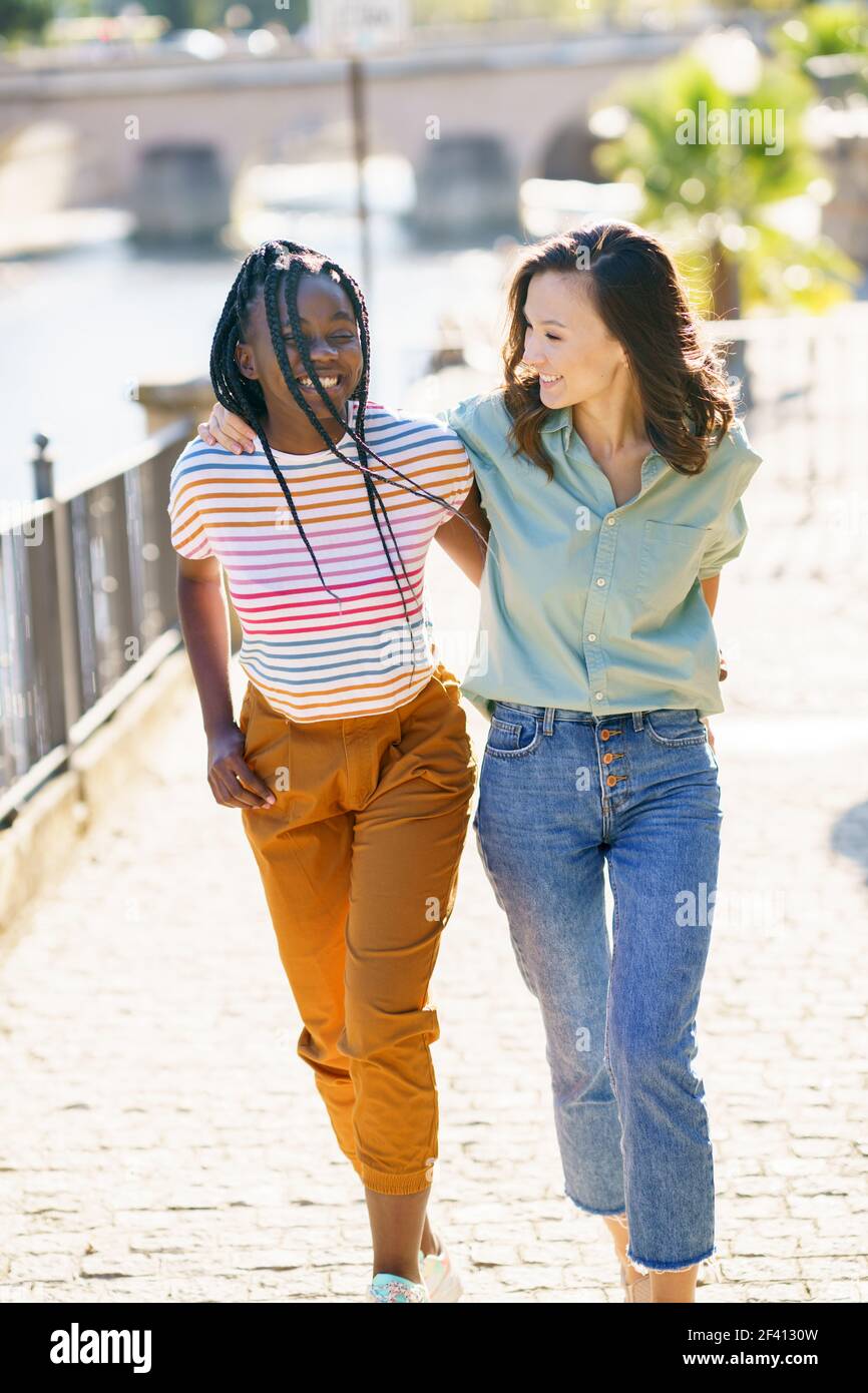 Zwei Freunde, die gemeinsam auf der Straße spazieren. Multiethnische Frauen... Zwei multiethnische Frauen, die gemeinsam auf der Straße spazieren. Stockfoto