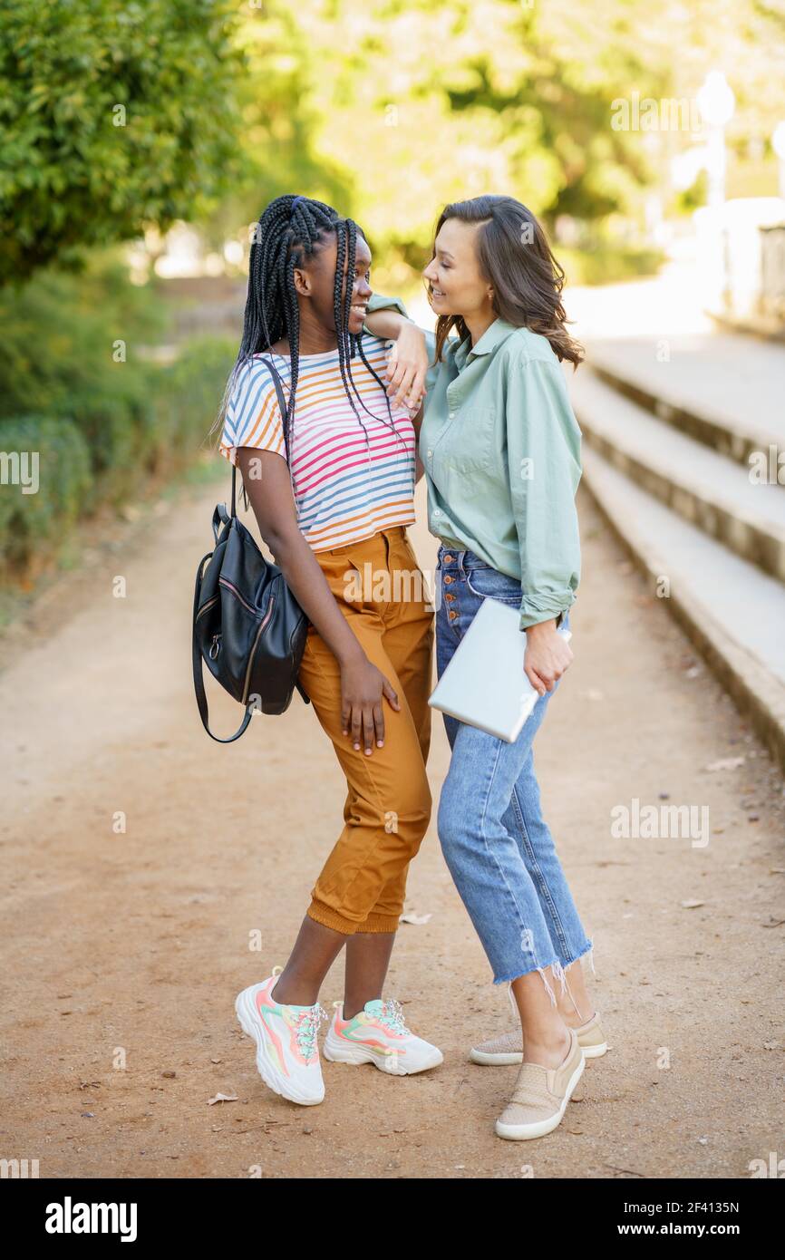 Zwei multiethnische Freundinnen posieren zusammen mit farbenfroher Freizeitkleidung im Freien. Mutliethnische Frauen... Zwei multiethnische Frauen posieren zusammen mit farbenfroher Freizeitkleidung Stockfoto