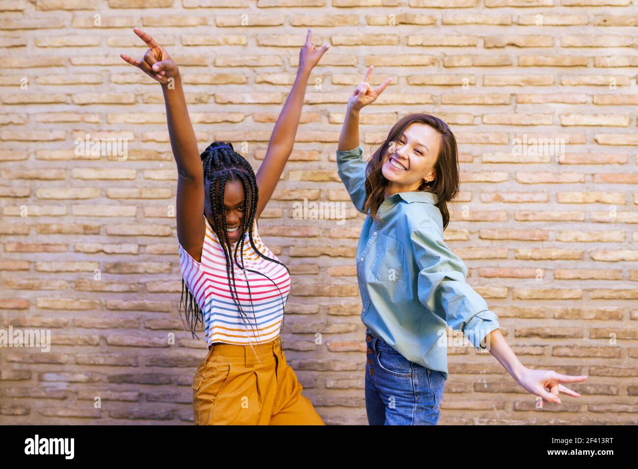 Zwei Freunde haben Spaß zusammen zeigen Zeichen der Hörner. Multiethnische Frauen... Zwei multiethnische Frauen haben Spaß zusammen zeigen Zeichen der Hörner. Stockfoto