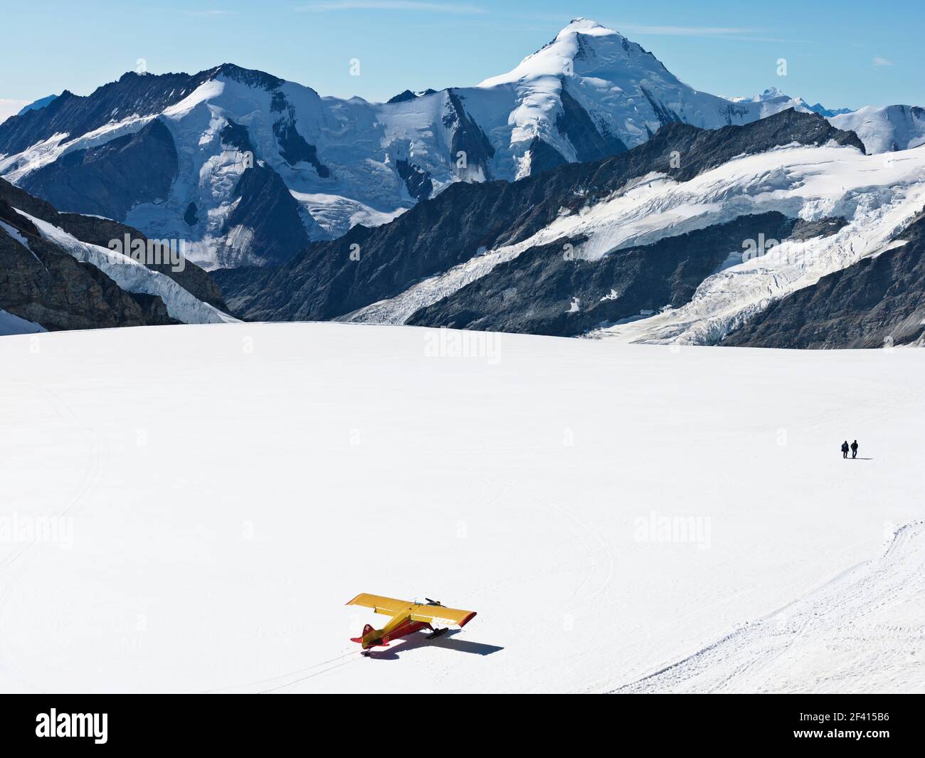 Schweiz Jungfraujoch-Top of Europe. Flugzeug auf Gletscher mit Bergen im Hintergrund und zwei Personen zu Fuß entfernt. Der Große Aletschgletscher. Stockfoto