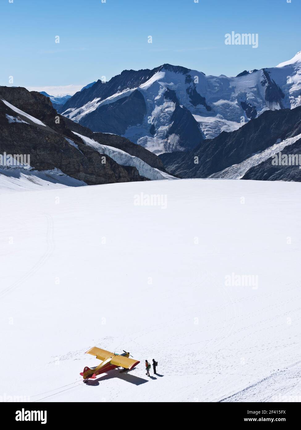Schweiz Jungfraujoch-Top of Europe. Flugzeug auf Gletscher mit Bergen im Hintergrund und zwei Personen zu Fuß entfernt. Der große Aletschgletscher, um 2 Stockfoto