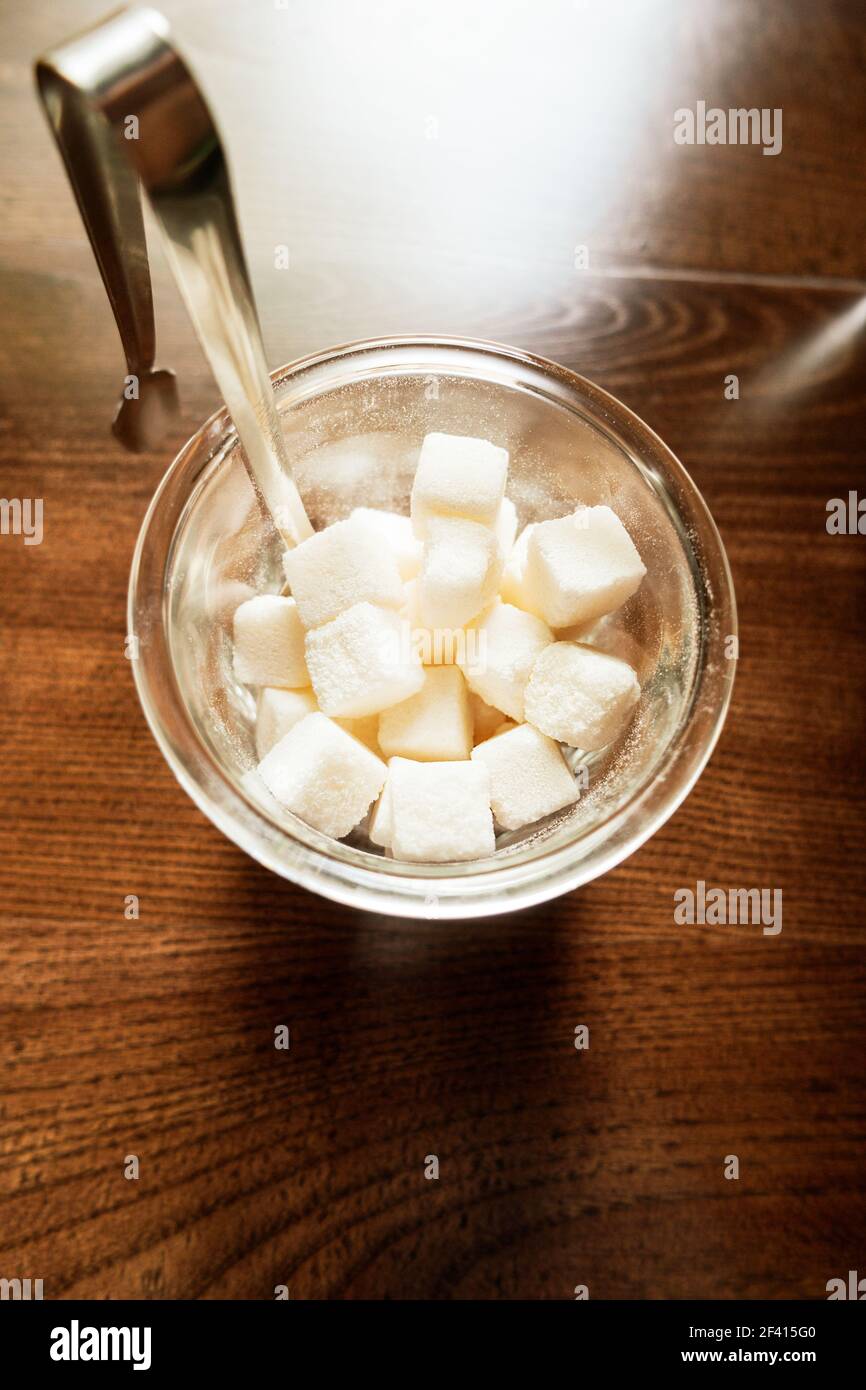 Weiße raffinierte Zuckerwürfel in der Zuckerdose Draufsicht auf Holzhintergrund. Zucker in der Schüssel Draufsicht auf Holzhintergrund Stockfoto