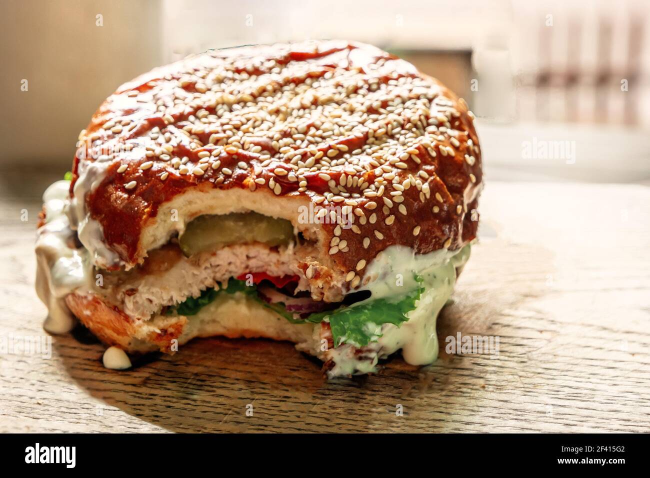 Vintage Farbe Bild von leckeren Hamburger auf Holzhintergrund mit Teil gebissen. Leckerer Hamburger auf Holzhintergrund mit teilweise abgebissen Stockfoto