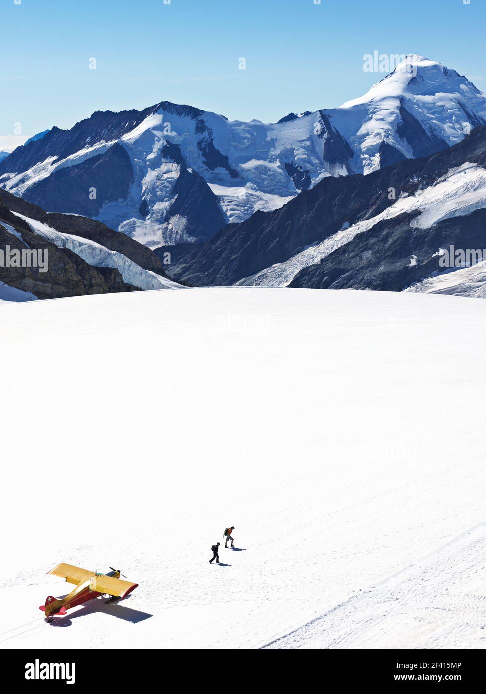 Schweiz Jungfraujoch-Top of Europe. Flugzeug auf Gletscher mit Bergen im Hintergrund und zwei Personen zu Fuß entfernt. Der Große Aletschgletscher, Stockfoto