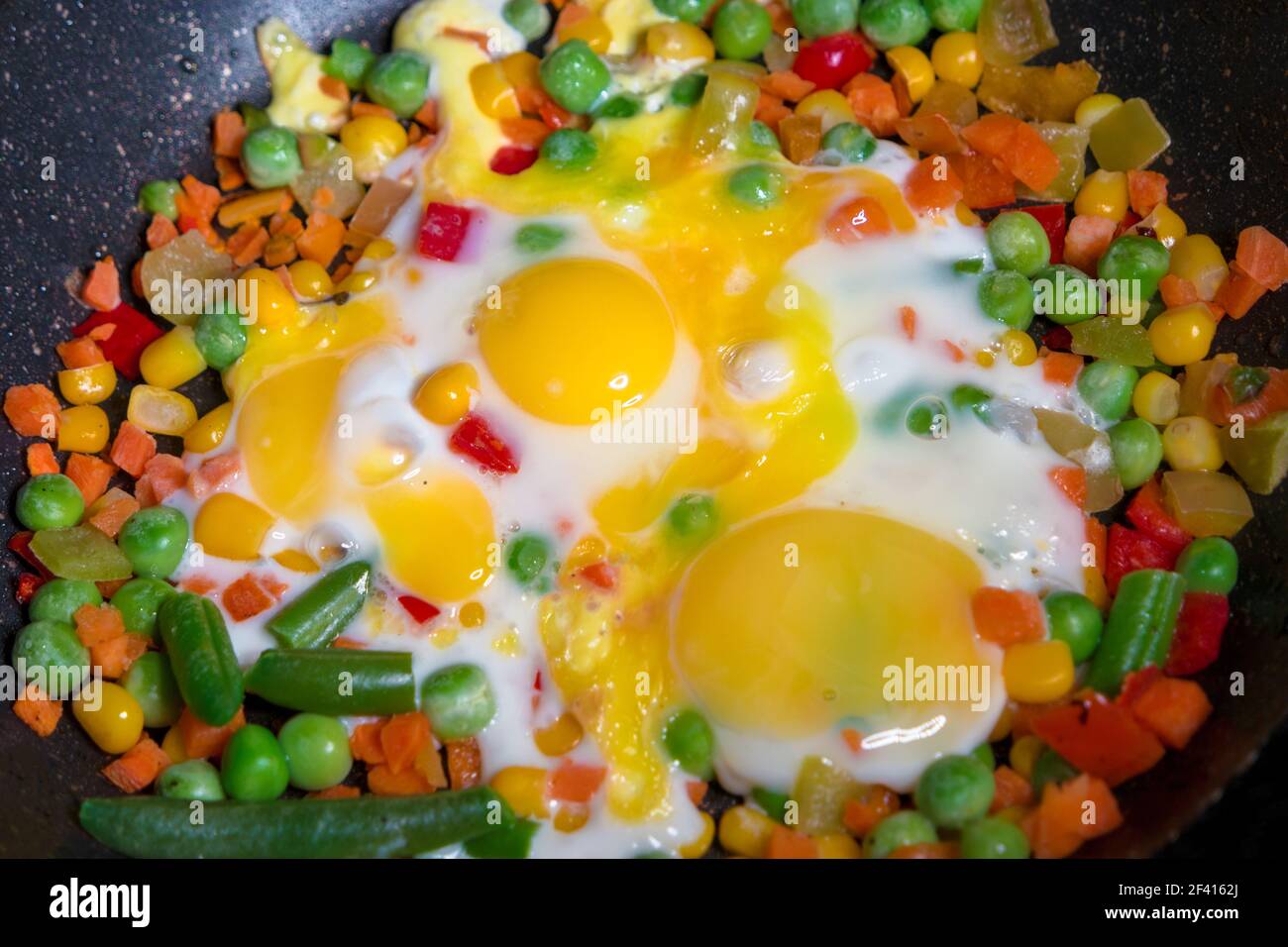 Spiegeleier mit gemischtem Gemüseschnitt, zubereitet auf einer Pfanne Nahaufnahme Blick von oben. Spiegeleier mit gemischtem Gemüseschnitt, zubereitet auf einer Bratpfanne Closeup Stockfoto