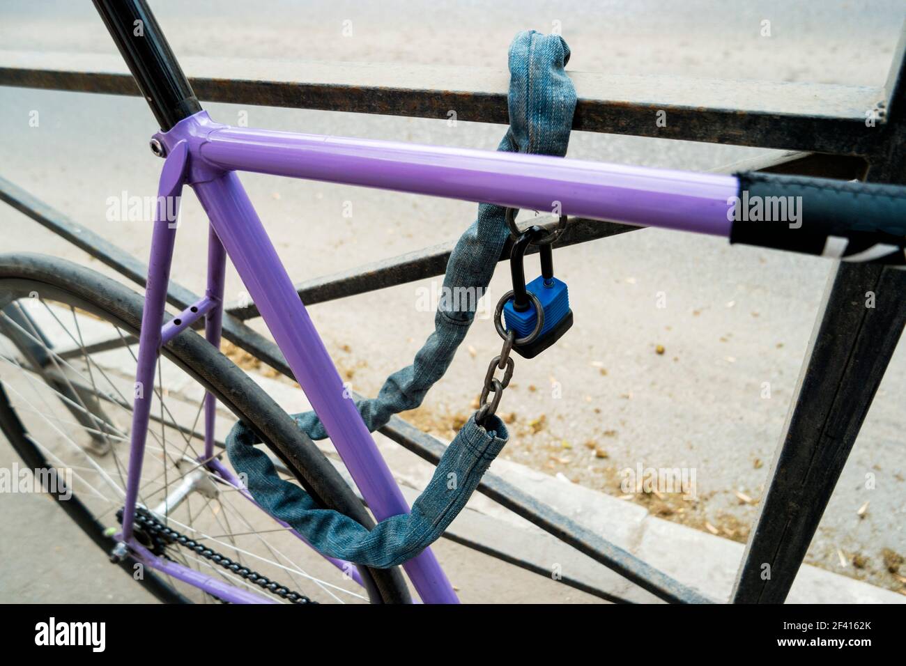 Eisenkette und Schloss auf einem alten Fahrrad von violetter Farbe. Abschließbar Fahrrad auf Fahrrad-Parkplatz im Freien. Eisenkette und Schloss auf einem alten Fahrrad von violetter Farbe Stockfoto