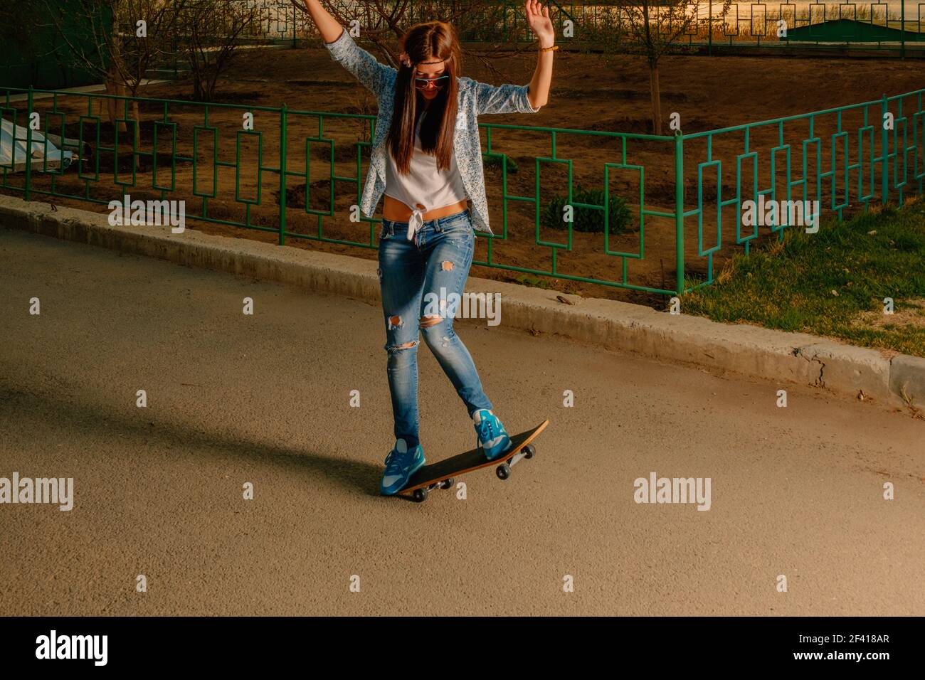 Hipster Mädchen machen Trick auf Skateboard in der Straße. Hipster Mädchen machen Trick auf Skateboard Stockfoto