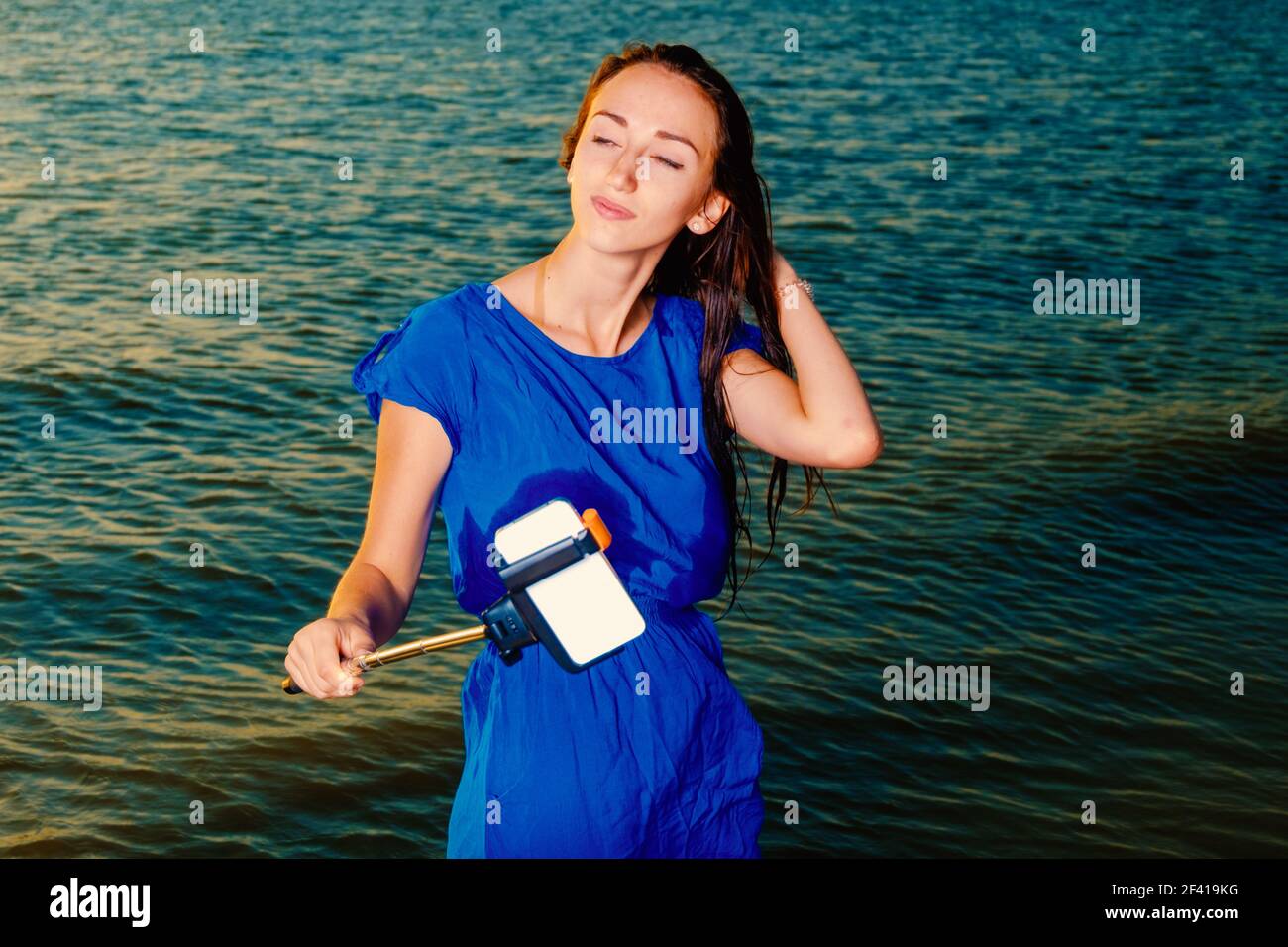 Geschlossenen Augen Frau machen selfie mit selfie Stick vor grünen Meer Wasser Stockfoto