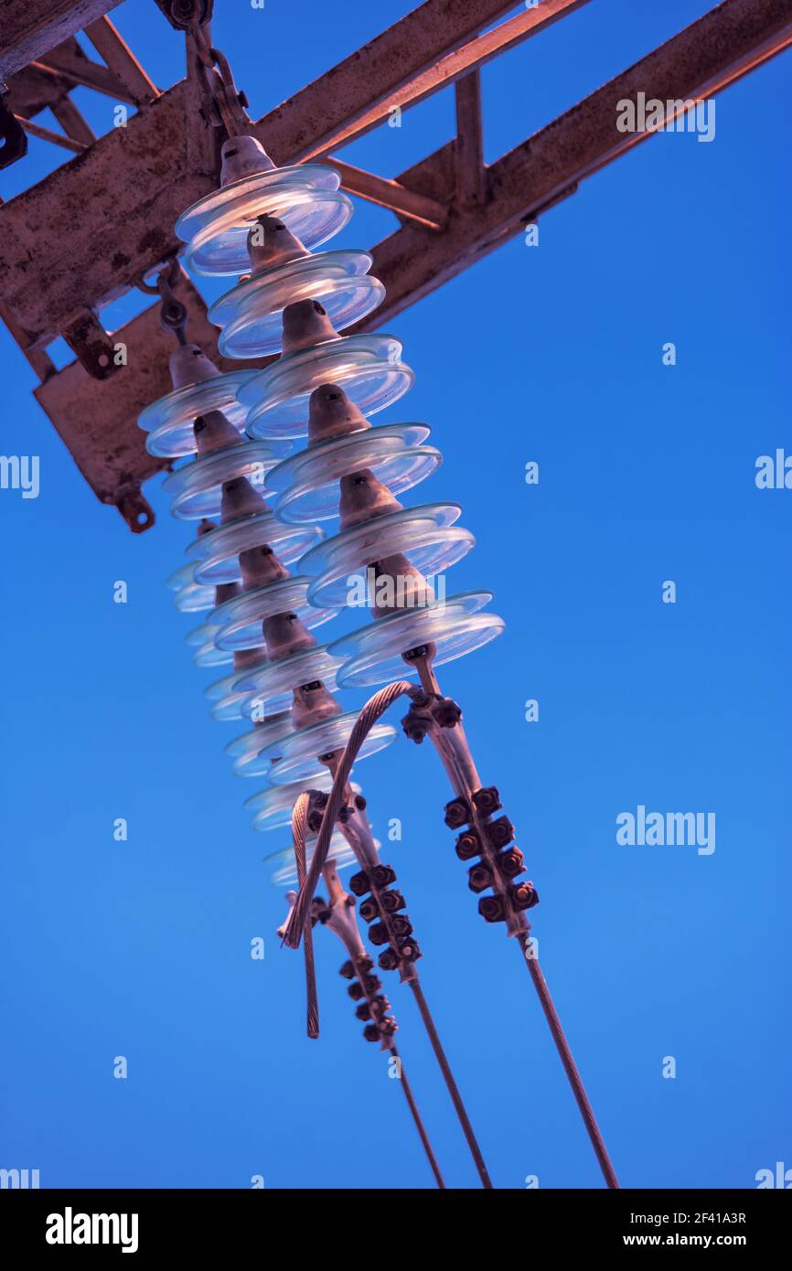 Hochspannungsisolator aus Glas auf elektrischer Linie gegen den blauen Himmel mit Copyspace. Hochspannungsisolator aus Glas auf elektrischer Linie gegen den blauen Himmel Stockfoto