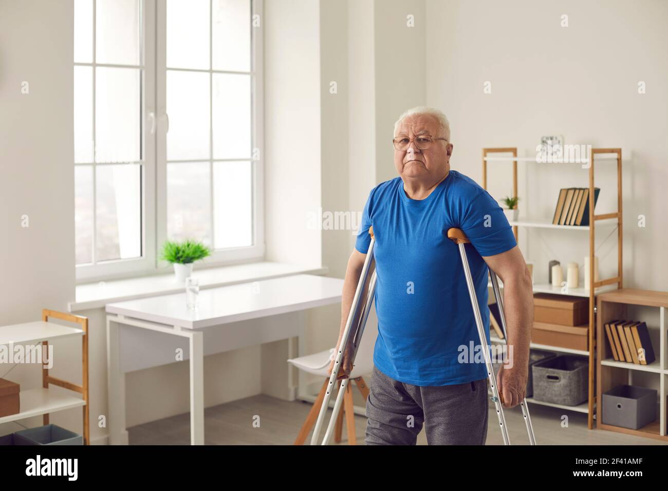 Ältere Person mit gebrochenem Bein oder körperlicher Behinderung beim Gehen mit Krücken zu Hause Stockfoto