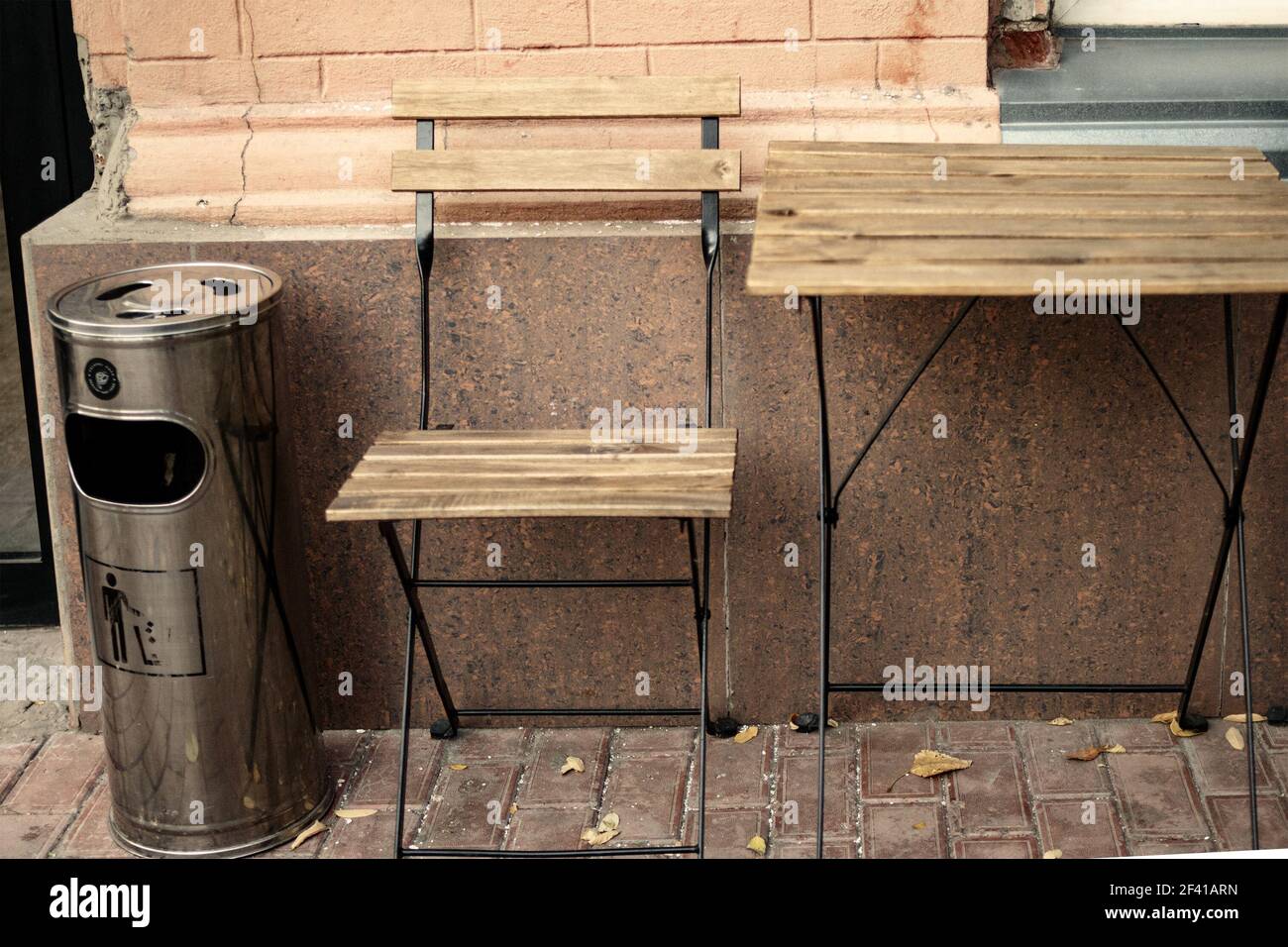 Holztisch und Stuhl draußen Cafe mit Mülleimer in der Nähe. Holztisch und Stuhl draußen Cafe mit Mülleimer Stockfoto