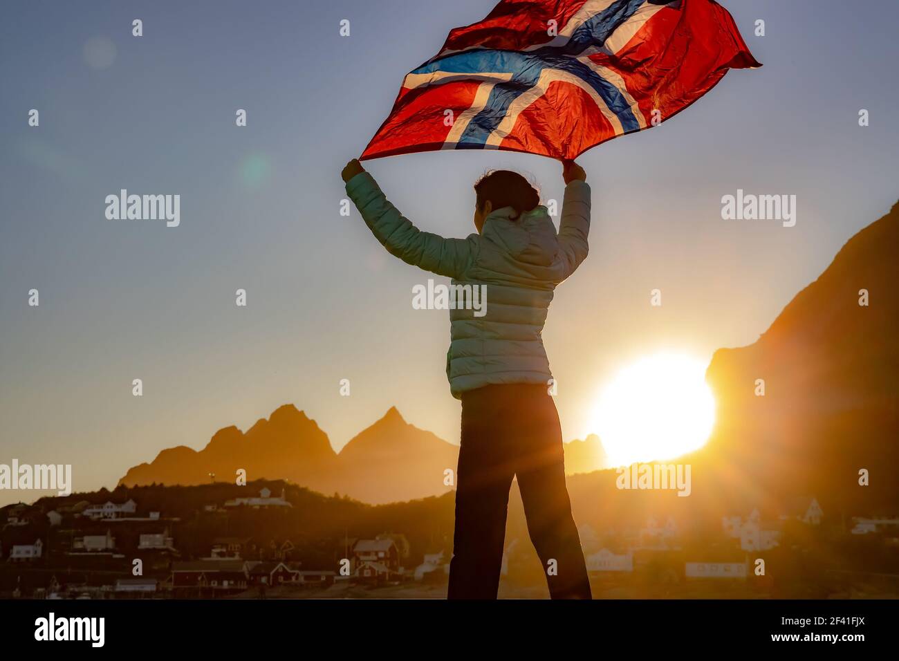 Die Frau winkt die Flagge Norwegens bei Sonnenuntergang Hintergrund Stockfoto