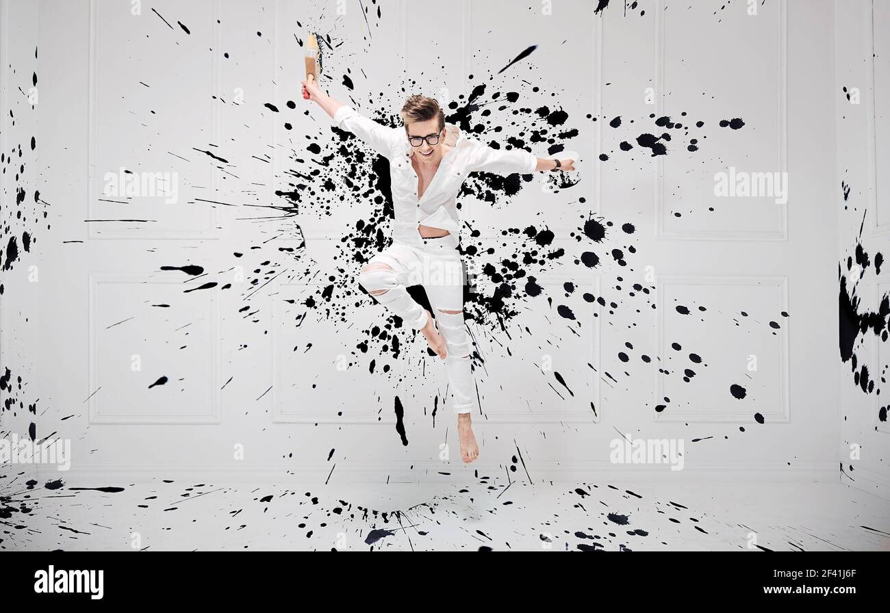 Hübscher junge Maler plantschen mit schwarzer Farbe Stockfoto