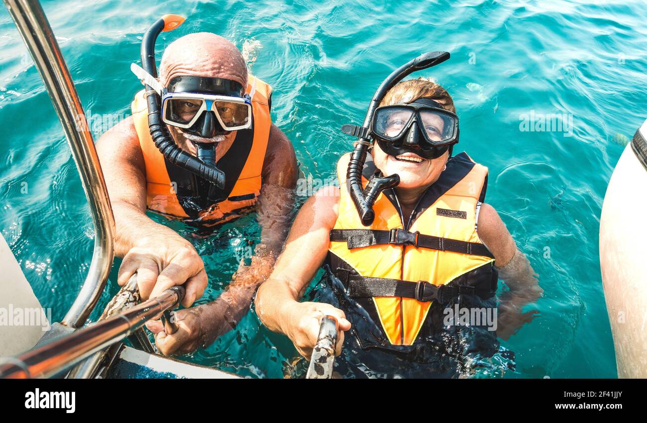 Rentnerpaar, das glücklich Selfie in tropischen Meer Ausflug mit Schwimmwesten und Schnorchelmasken - Bootsfahrt Schnorcheln in Exotische Szenarien Stockfoto