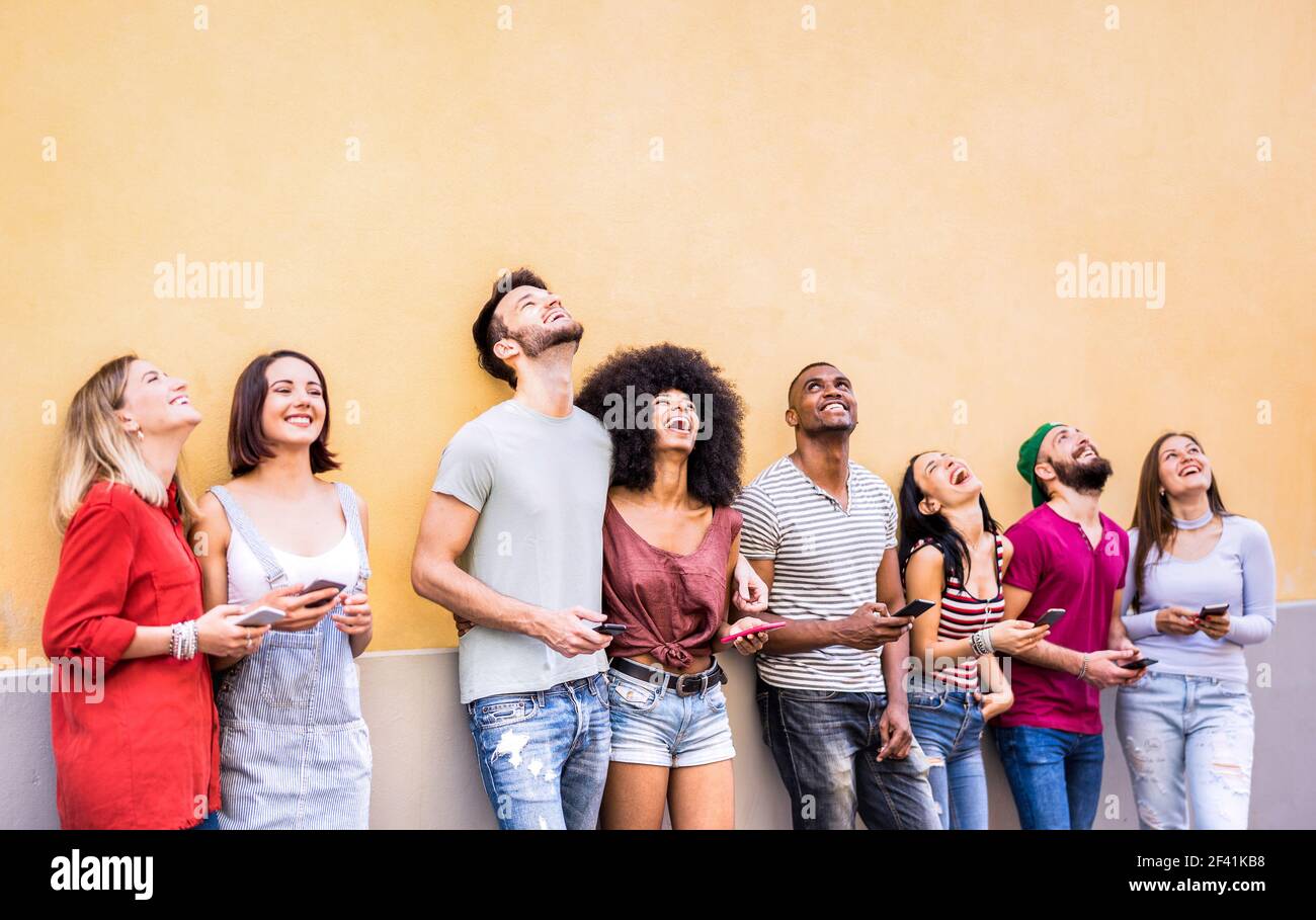 Multirassische Freunde haben Spaß mit Smartphone an der Wand an der Universität college Break - Junge Menschen süchtig nach mobilen Smartphones Stockfoto