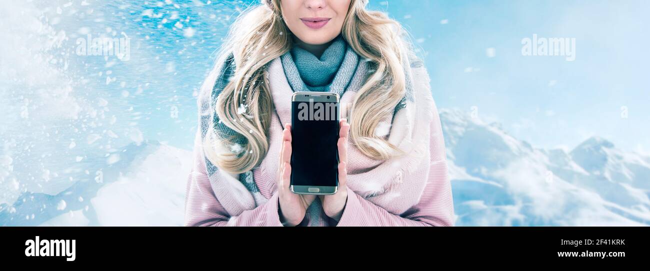 Hübsche blonde Dame mit einem Smartphone, Winterwetter Stockfoto