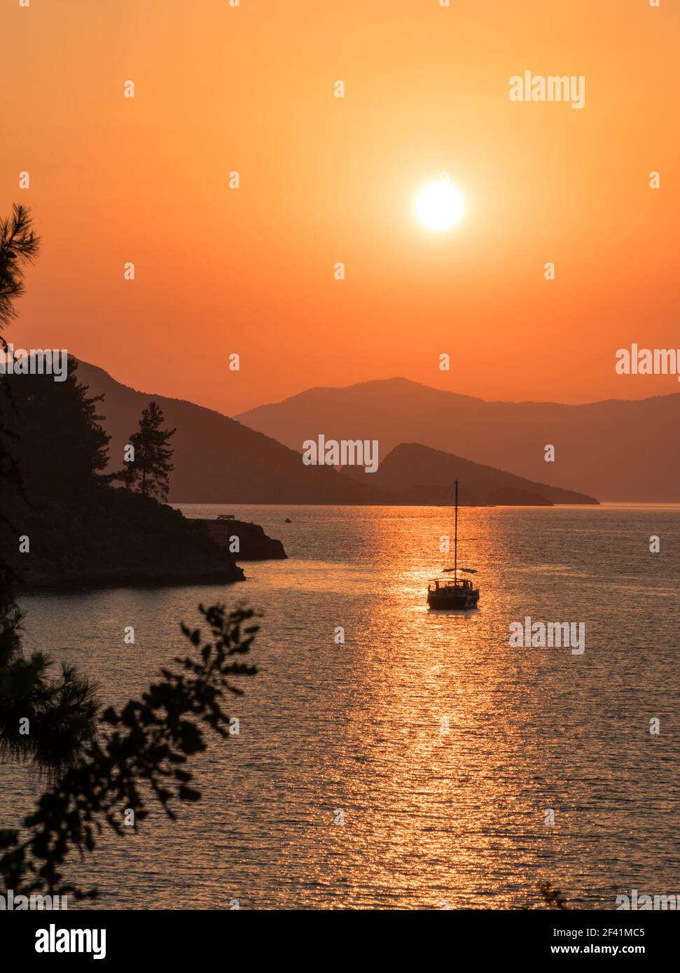 Ruhiges Meer und Sonnenuntergang. Die Sonne geht hinter den Hügeln im Horizont unter. Schöne Natur Hintergrund. Stockfoto