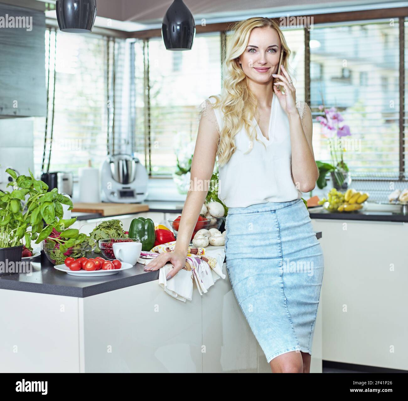 Hübsche, blonde Frau realxing in der Sommerküche Stockfoto
