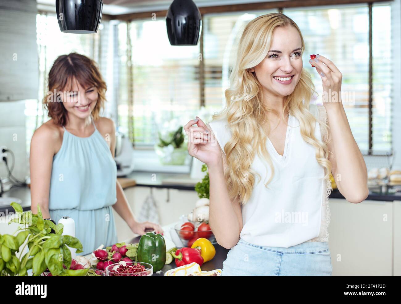 Zwei fröhliche Freundinnen entspannen in der hellen Küche Stockfoto