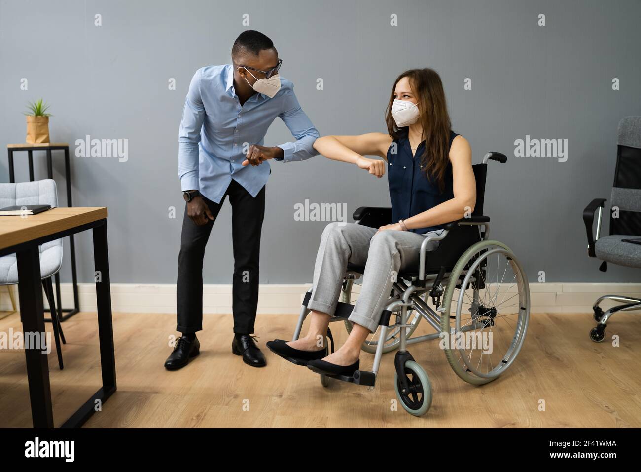 Behinderte Im Rollstuhl Ellenbogen Bump Im Büro Stockfoto