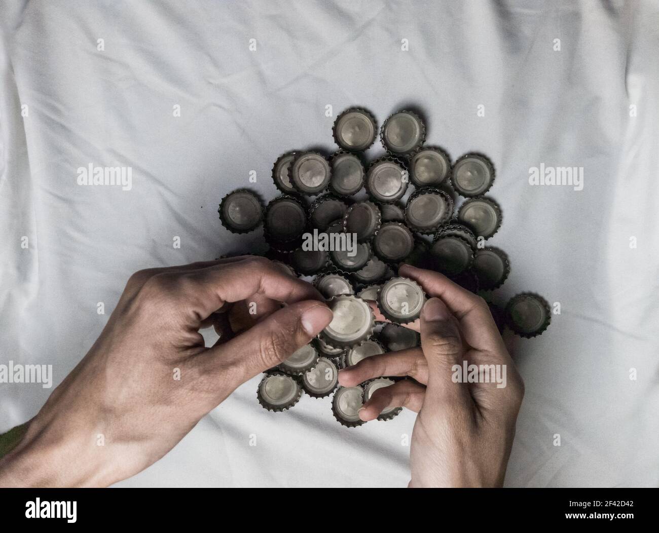 Hände halten eine Gruppe von Flaschenverschlüssen mit offenen Handflächen, Recycling-Kultur. Objekte auf weißem Hintergrund isoliert.Auswahl eines der Flaschenverschlüsse. Stockfoto