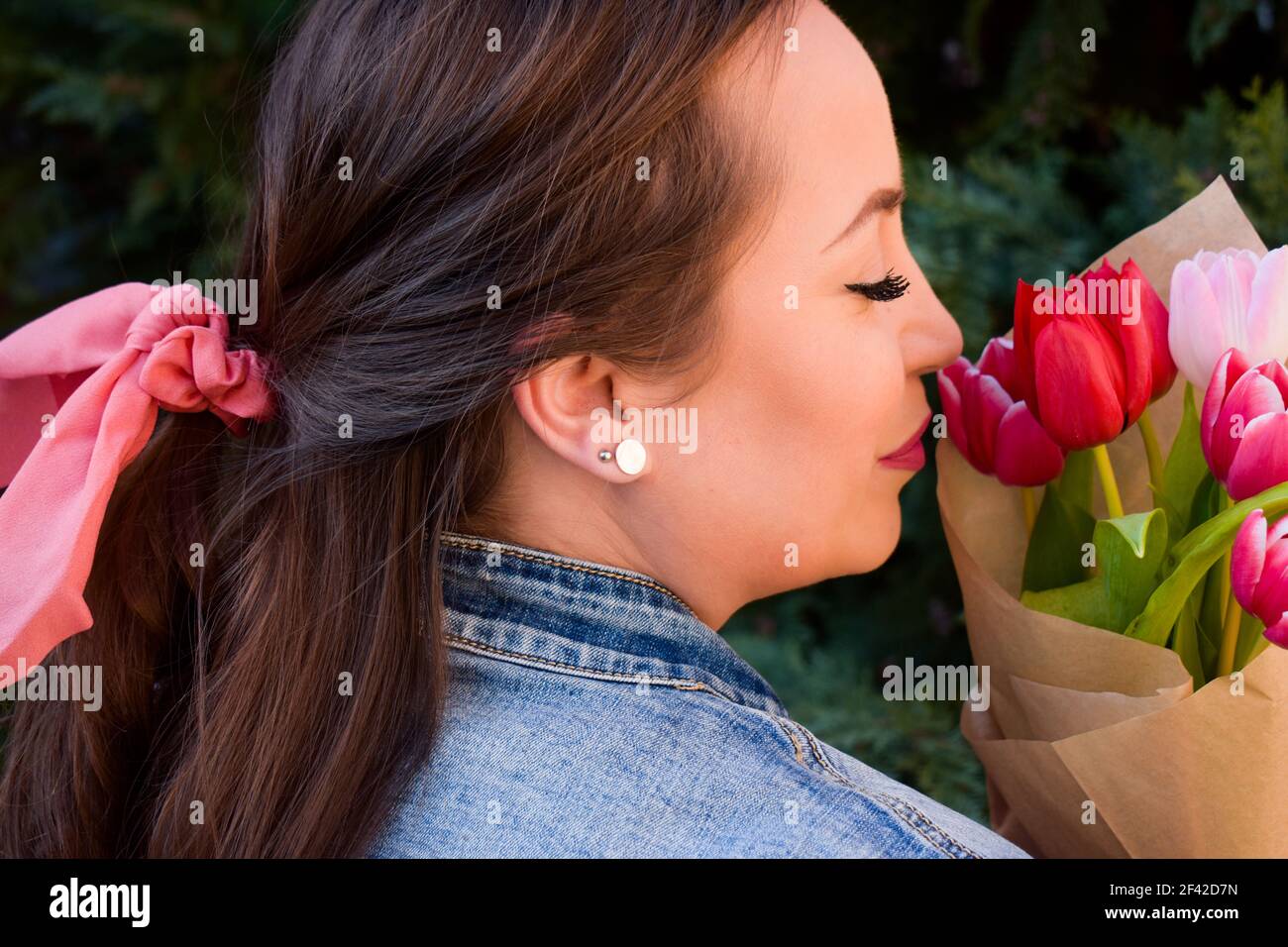 Frau mit einer rosa Schleife im Haar, die Tulpe hält Bouquet Stockfoto