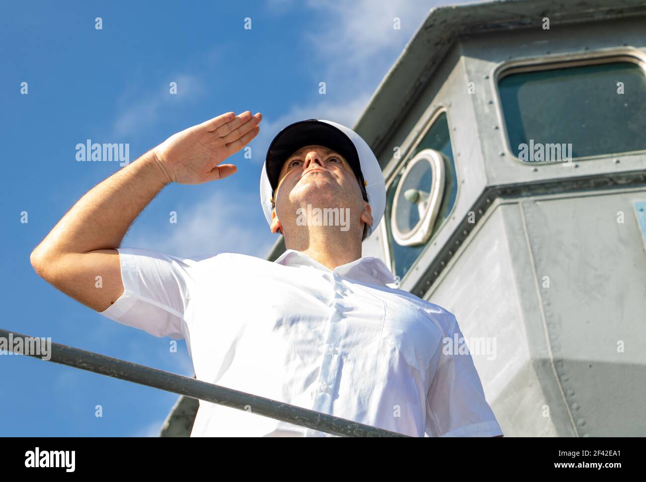 Der Kapitän steht auf der Galerie der Schifffahrtsbrücke und grüßt. Stockfoto