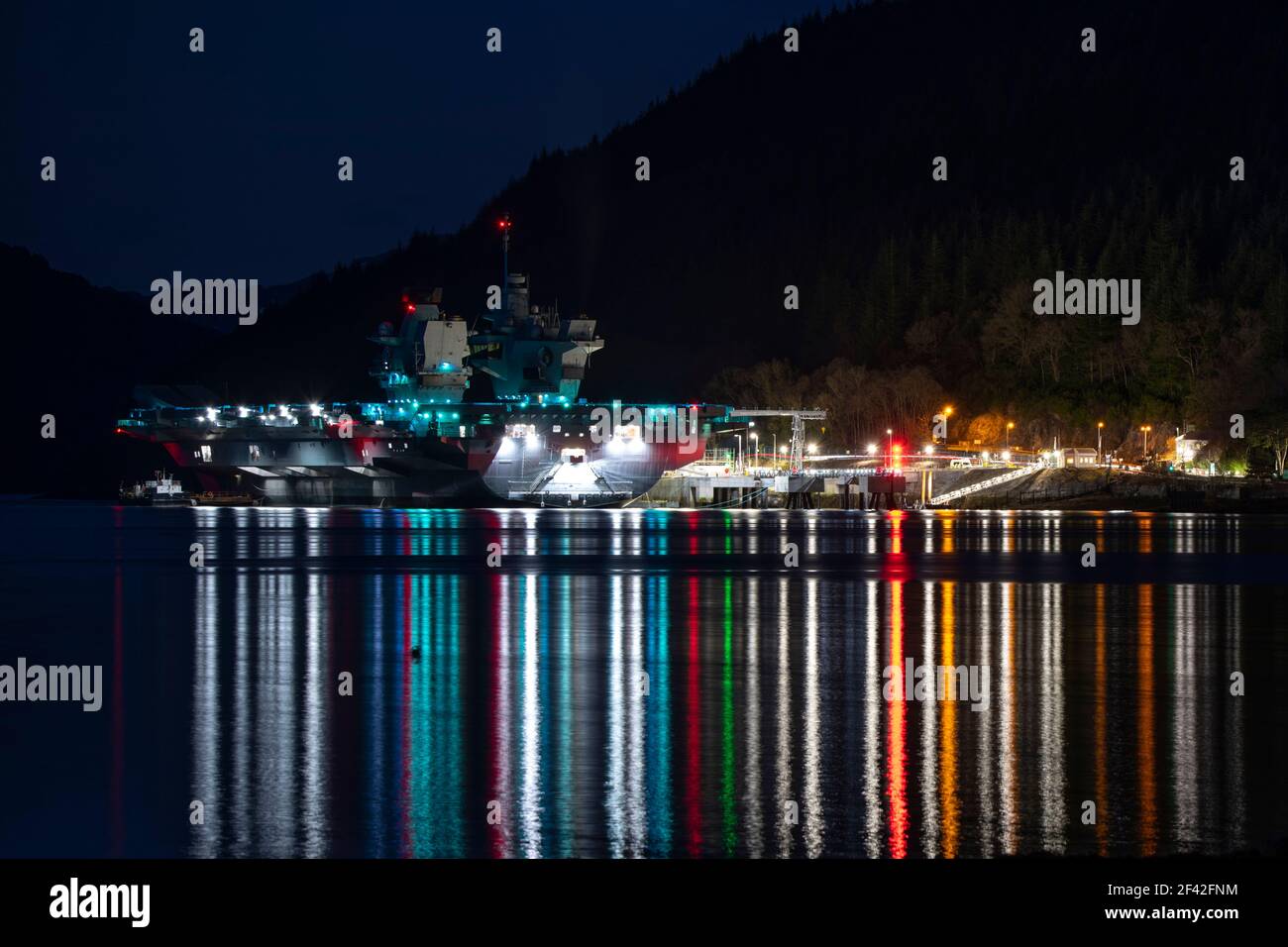 Finnart, Loch Long, Schottland, Großbritannien. März 2021, 18th. IM BILD: HMS Queen Elizabeth um nigh9t mit Reflexionen auf dem Wasser von Loch Long. HMS Queen Elizabeth ist das größte und fortschrittlichste Kriegsschiff, das jemals für die Royal Navy gebaut wurde. Die Aircraft Carrier liegt derzeit an der Seite des Long Loch in Glenmallan und übernimmt Treibstoff, Munition und andere Vorräte, bevor die Marineübungen, die Teil der britischen Carrier Strike Group 2021 sind, durchgeführt werden. Das Schiff soll am Sonntag abreisen. Quelle: Colin Fisher/Alamy Live News Stockfoto