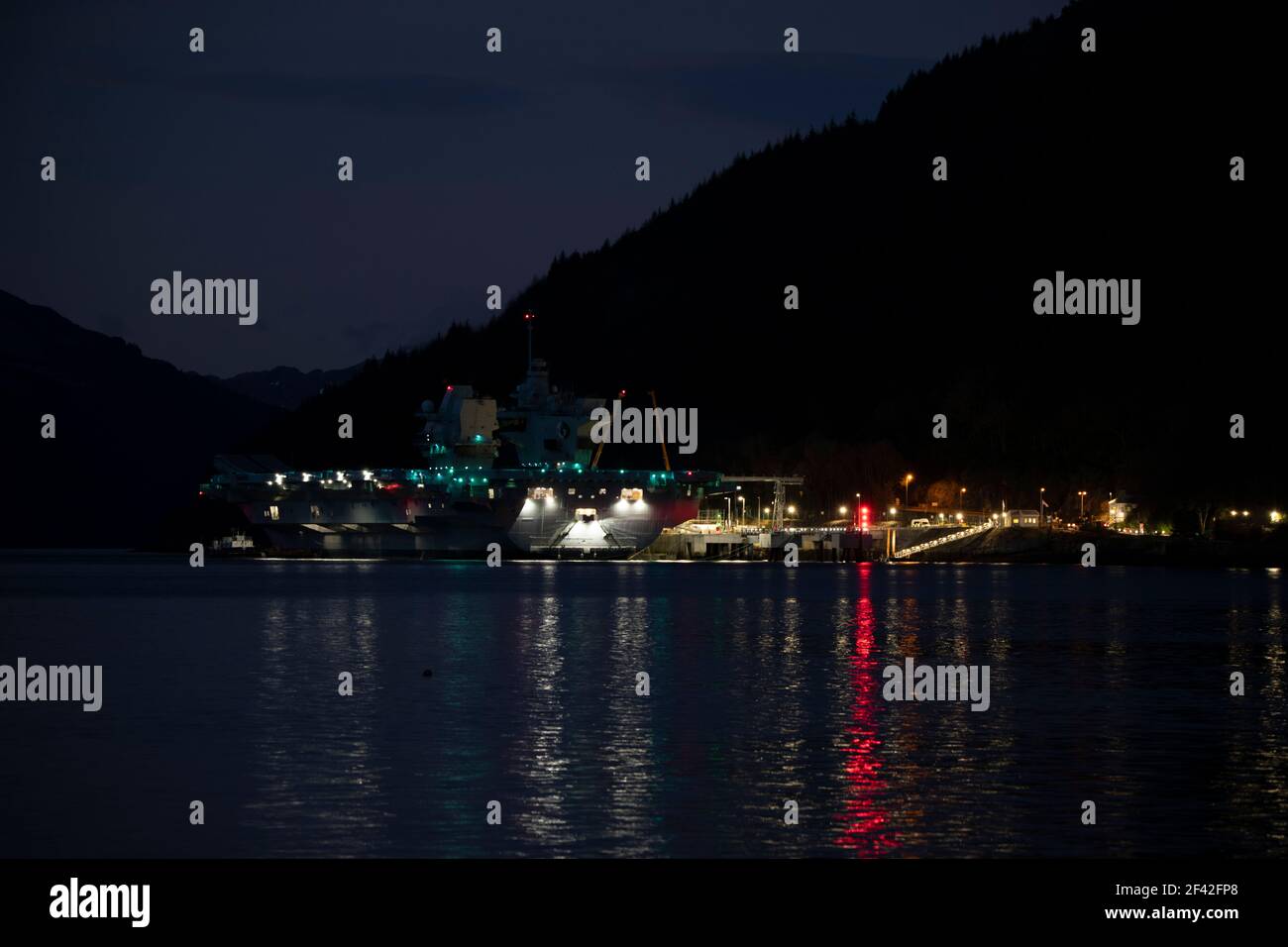 Finnart, Loch Long, Schottland, Großbritannien. März 2021, 18th. IM BILD: HMS Queen Elizabeth um nigh9t mit Reflexionen auf dem Wasser von Loch Long. HMS Queen Elizabeth ist das größte und fortschrittlichste Kriegsschiff, das jemals für die Royal Navy gebaut wurde. Die Aircraft Carrier liegt derzeit an der Seite des Long Loch in Glenmallan und übernimmt Treibstoff, Munition und andere Vorräte, bevor die Marineübungen, die Teil der britischen Carrier Strike Group 2021 sind, durchgeführt werden. Das Schiff soll am Sonntag abreisen. Quelle: Colin Fisher/Alamy Live News Stockfoto