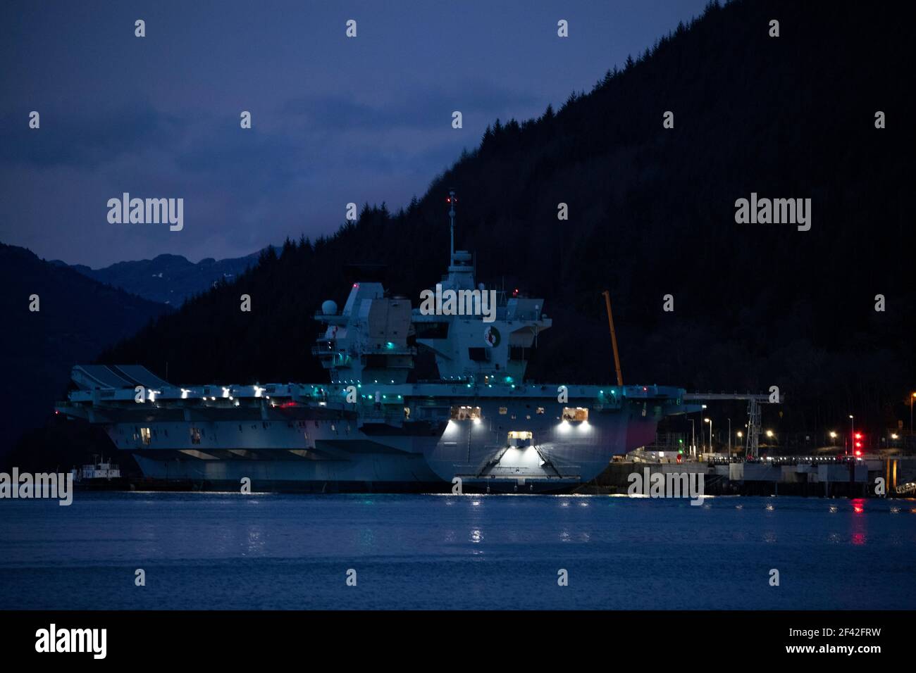Finnart, Loch Long, Schottland, Großbritannien. März 2021, 18th. IM BILD: HMS Queen Elizabeth um nigh9t mit Reflexionen auf dem Wasser von Loch Long. HMS Queen Elizabeth ist das größte und fortschrittlichste Kriegsschiff, das jemals für die Royal Navy gebaut wurde. Die Aircraft Carrier liegt derzeit an der Seite des Long Loch in Glenmallan und übernimmt Treibstoff, Munition und andere Vorräte, bevor die Marineübungen, die Teil der britischen Carrier Strike Group 2021 sind, durchgeführt werden. Das Schiff soll am Sonntag abreisen. Quelle: Colin Fisher/Alamy Live News Stockfoto