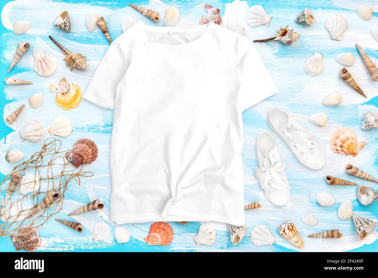 T-Shirt Mockup flach Lay. Meeresmuscheln auf blauem Holzhintergrund Stockfoto