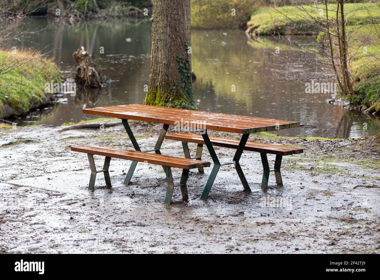 Holzpicknicktisch an einem See an einem regnerischen Tag. Stockfoto