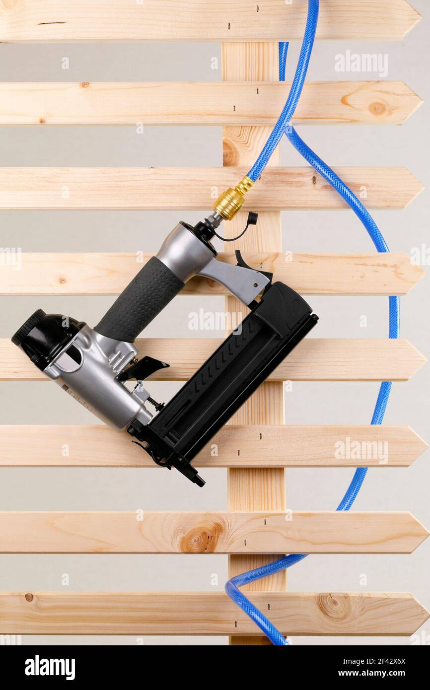 Ein Druckluftnagler mit Druckschlauch auf einem Holz Zaun Stockfoto