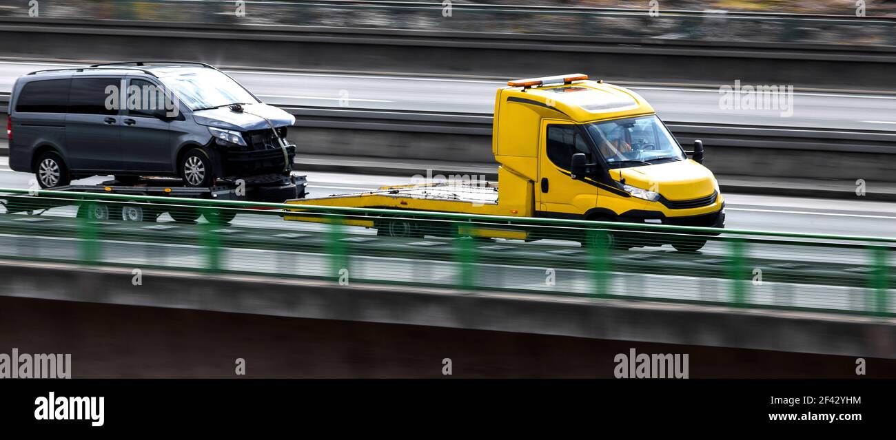 Ein Abschleppwagen mit einem heruntergekommenen Fahrzeug, das auf der Fahrt ist Ein Autobahnpanorama Stockfoto