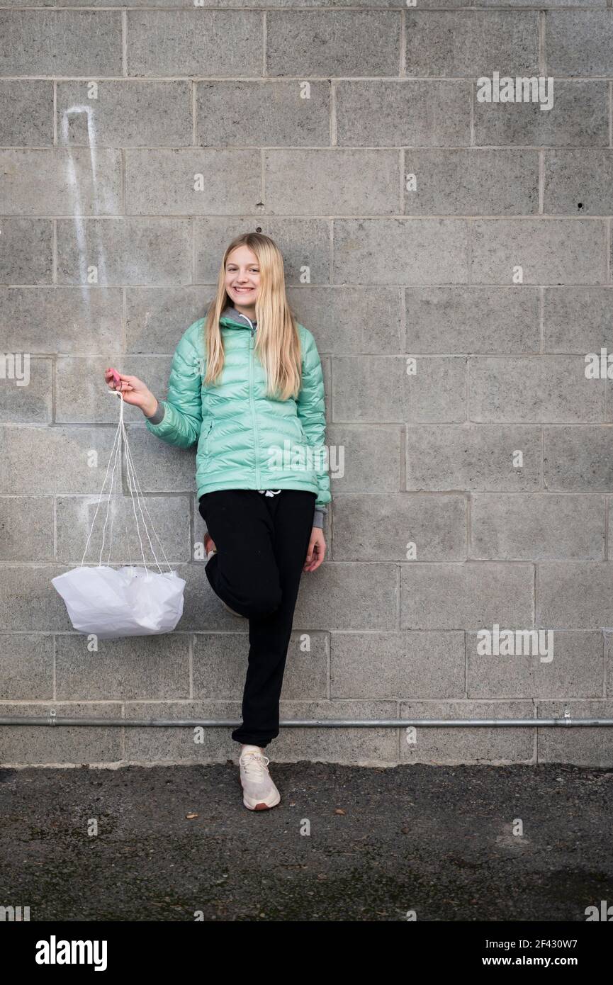 Blonde Mädchen Halten Papier Fallschirm Lächelnd In Der Nähe Zement Ziegelwand Stockfoto