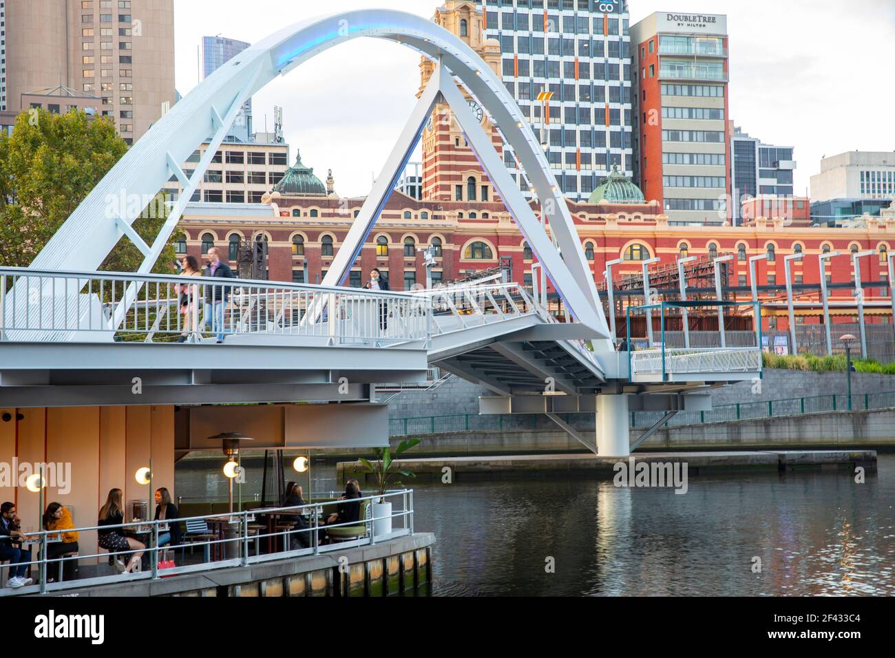 Melbourne City Centre und yarra River bei Sonnenuntergang, Leute essen in einem Restaurant unterhalb evan Walker Bridge, Victoria, Australien Stockfoto