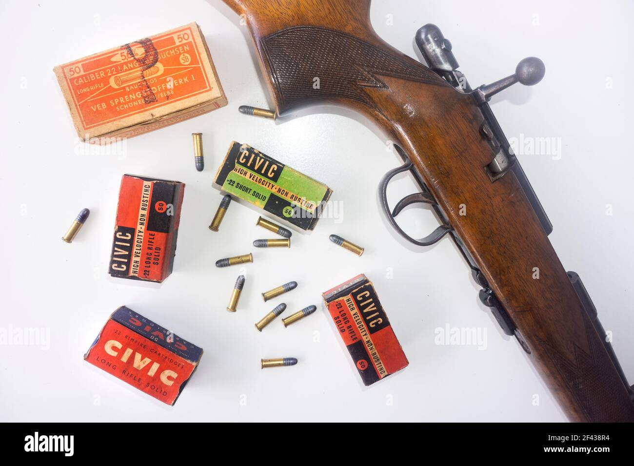 Jagdkonzept mit einem Bolt Action Gewehr und Vintage-Boxen von Kaliber .22 Kugeln und lose Kugeln auf weißem Hintergrund verstreut. Stockfoto