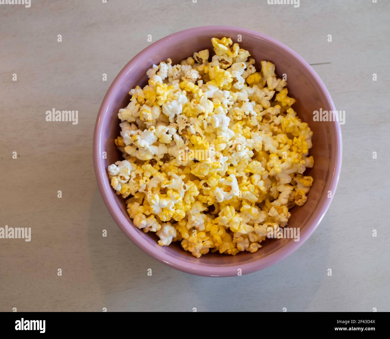 Popcorn, oder poppte Mais, in einer rosa Schüssel auf einem Tisch. Stockfoto