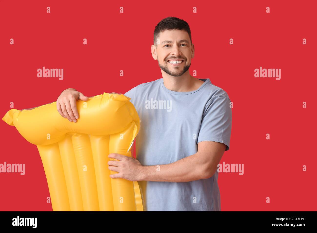 Schöner Mann mit aufblasbarer Matratze auf farbigem Hintergrund Stockfoto