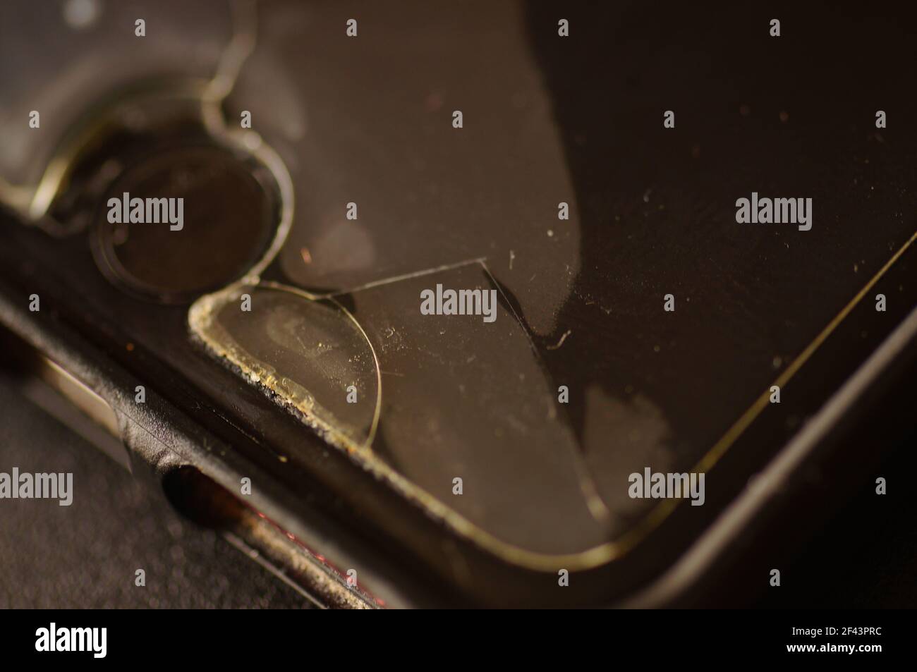 Smartphone-Schutzglas – beschädigt, gerissen, abgenutzt. Alter Bildschirmschutz. Schmutziges, schwarzes, abgenutztes Telefon. Stockfoto