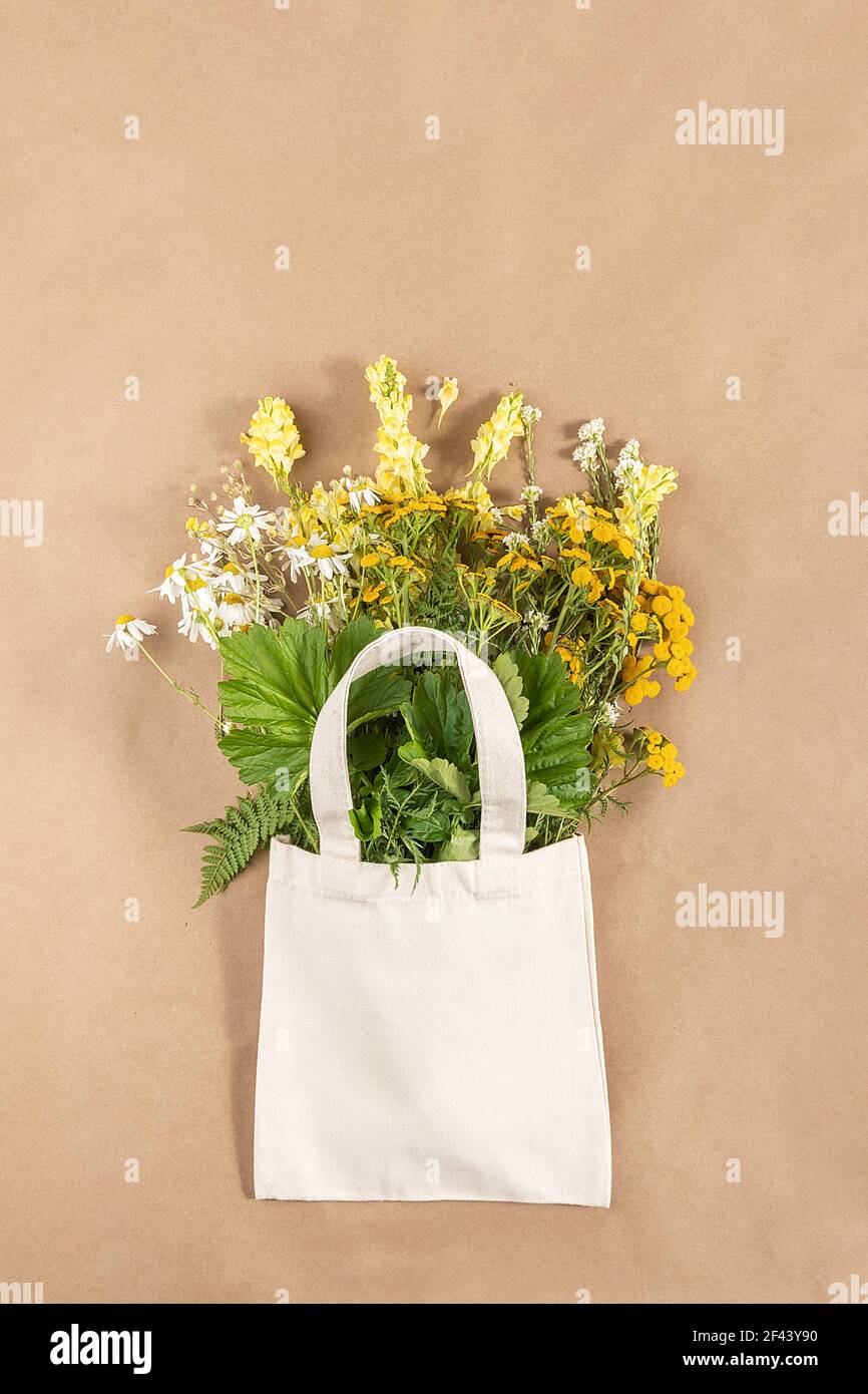 Bouquet von Feldblumen in Stoff Öko-Tasche auf beigem Hintergrund. Konzept kein Kunststoff und kein Abfall. Mockup von oben. Stockfoto