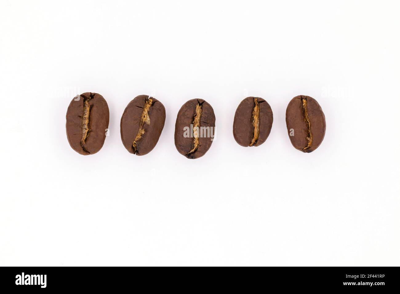 Geröstete Kaffeebohnen, Nahaufnahme. Kaffeebohne isoliert auf weiß. Fünf Samen in einer Reihe Stockfoto