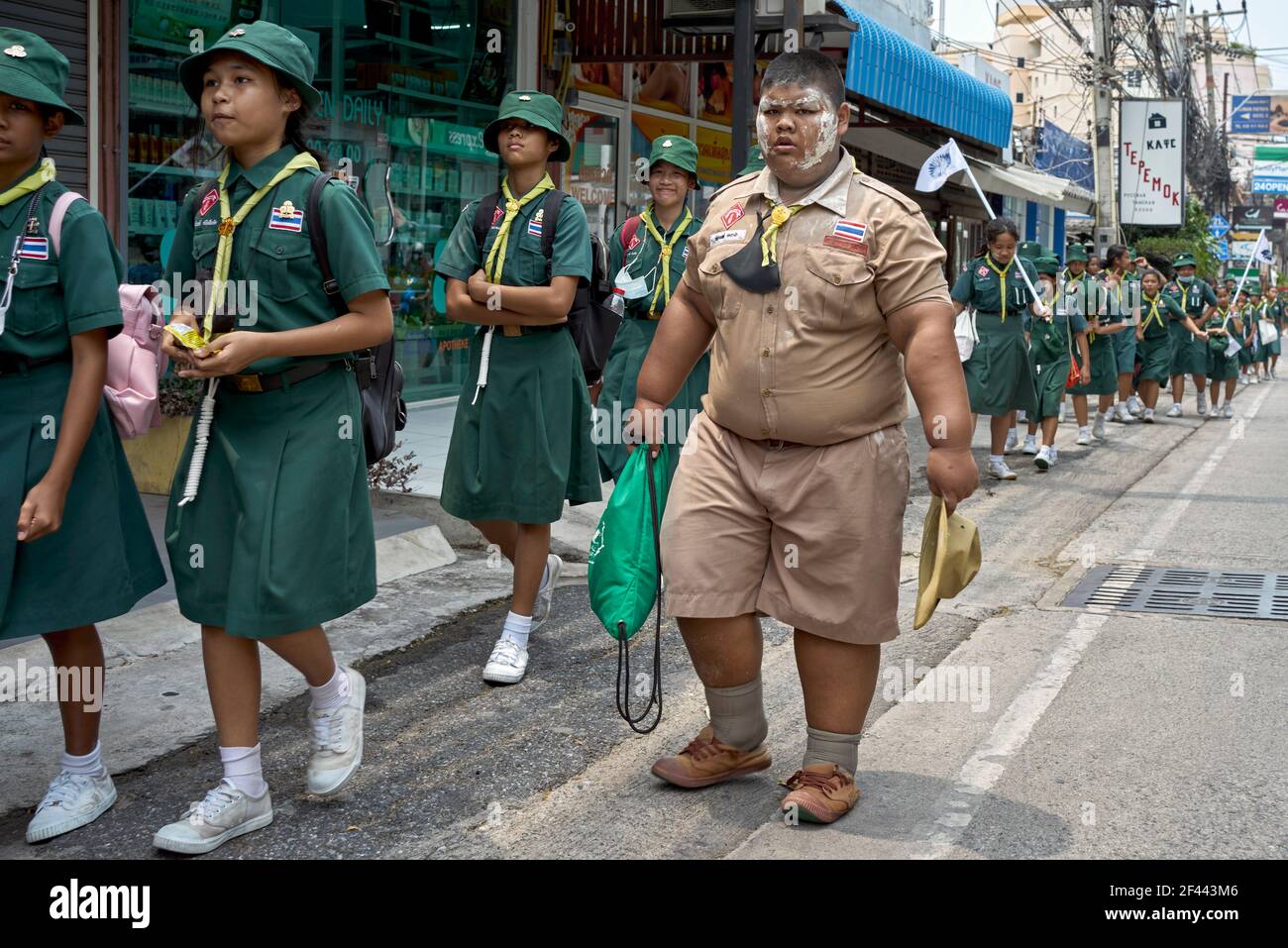 Adipösen Jungen Scout mit Mädchen Führer Gruppe von Schulkindern zu Fuß in einer Straßenparade. Thailand Südostasien Stockfoto