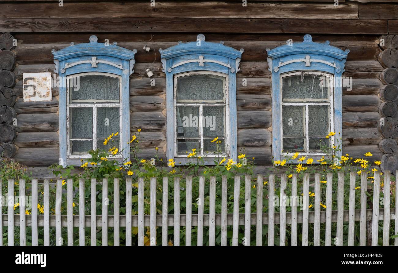 Russische alte Holzhütte mit weißem Zaun und Yelloow-Blumen in Tyumenevo, Sibirien, Russland. Stockfoto