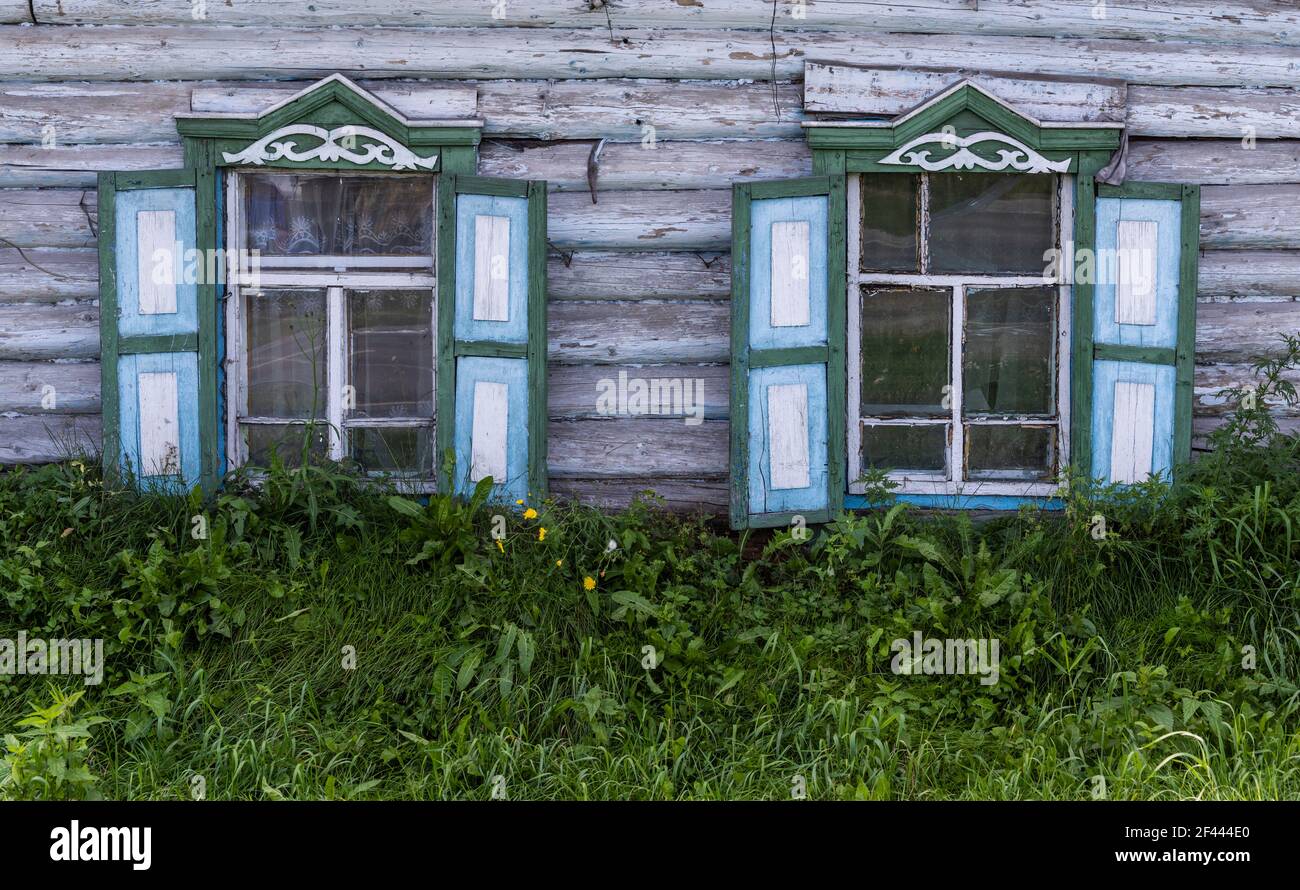Russische alte weiße Holzhütte mit hellgrünen und blauen Fensterläden in Krasnojarsk, Sibirien, Russland. Stockfoto