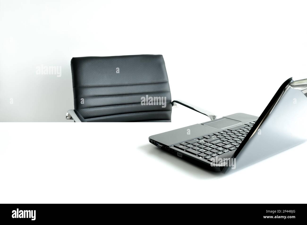 Laptop oder Notebook-Computer auf dem Tisch mit leerem Arbeiten Stuhl im weißen Zimmer Stockfoto