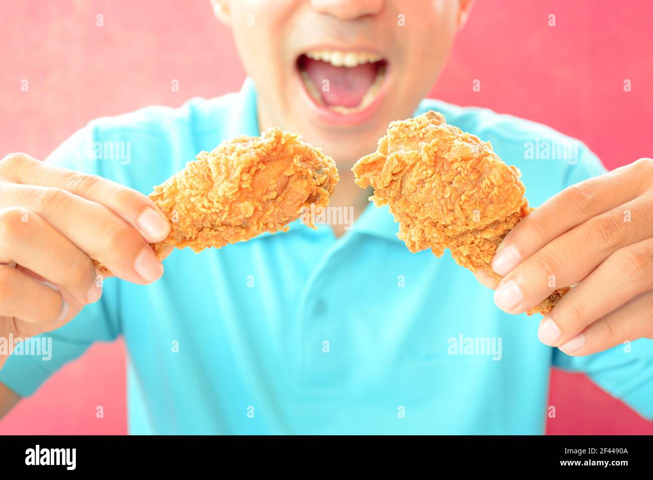 Ein Mann mit Öffnung Mund über frittierte essen Hähnchenbeine oder Drumsticks Stockfoto